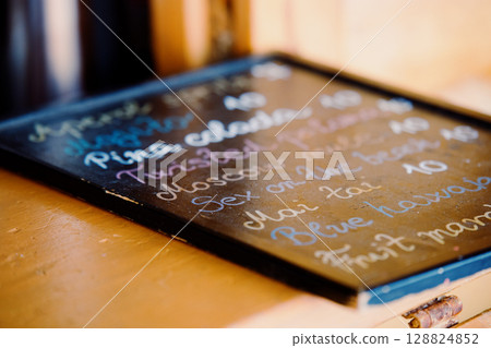 Alcoholic cocktail menu on the bar counter. Wooden board with handwritten chalk 128824852