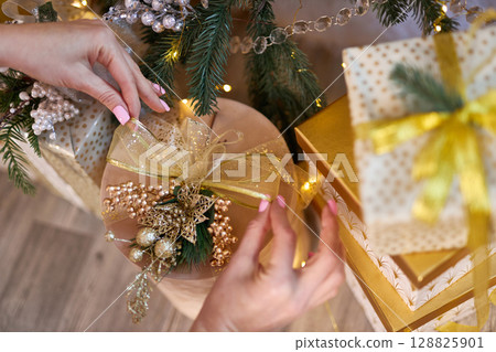 Female Hands Decorating Christmas Gift Female Hands Decorating Christmas Gift 128825901