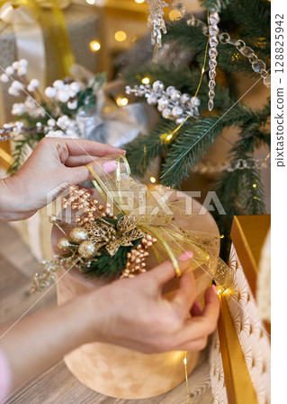 Female Hands Decorating Christmas Gift 128825942