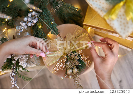 Female Hands Decorating Christmas Gift 128825943
