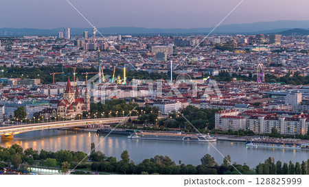 Aerial panoramic view over Vienna city with skyscrapers, historic buildings and a riverside promenade day to night timelapse in Austria. 128825999