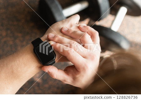 Person in gym with smartwatch on wrist, set against background with gym equipment. Check fitness progress in apps. Mock up. Person in gym with smartwatch on wrist, set against background with gym equipment. Check fitness progress in apps. Mock up. 128826736
