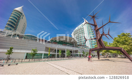 Visitors coming in and out of the Vasco da Gama Shopping mall timelapse hyperlapse, modern towers in the background. Lisbon, Portugal 128826918