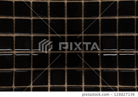 Glossy black mosaic tiles arranged in a grid pattern on a neutral background for accentuating modern Glossy black mosaic tiles arranged in a grid pattern on a neutral background for accentuating modern 128827136