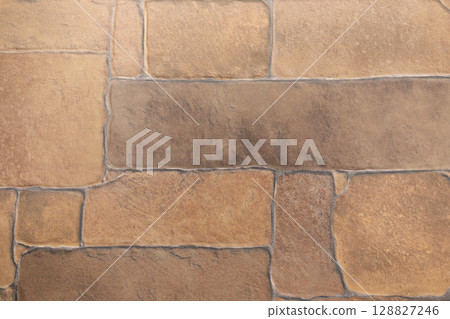 Textured stone wall with warm earthy tones in a close-up view highlighting the natural patterns and 128827246