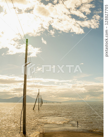 Electric poles stretching out over the Ariake Sea and the sea road, a tranquil scene before dusk Electric poles stretching out over the Ariake Sea and the sea road, a tranquil scene before dusk 128827705