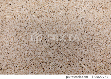 Granite countertop surface showcasing a light beige pattern with specks in a residential kitchen Granite countertop surface showcasing a light beige pattern with specks in a residential kitchen 128827737