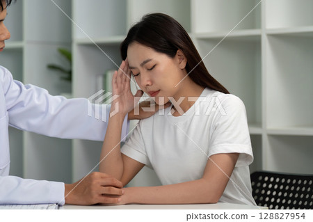 Healthcare Consultation. Doctor providing support to a woman experiencing headache symptoms. 128827954