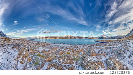 Panoramic view over snowy fjord with scattered houses Panoramic view over snowy fjord with scattered houses 128828276