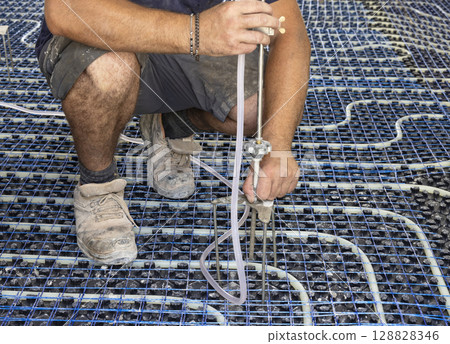 Man installing self levelling tripod for HVAC in a new building. Modern construction system 128828346