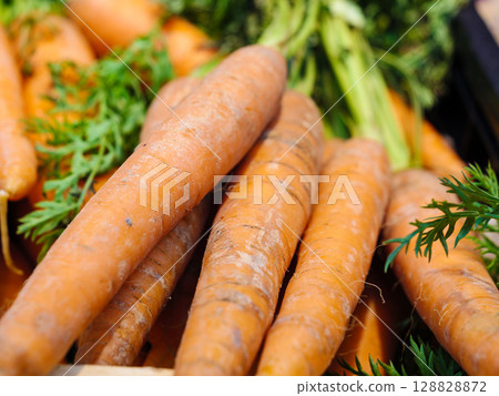 Orange carrots with green leaves in market. Vegetables background Orange carrots with green leaves in market. Vegetables background 128828872