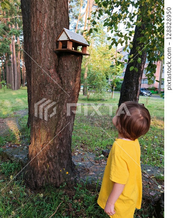 Wooden bird feeder and sparrow Bird feeder, wooden bird house, feeding for birds. child has his back to camera 128828950