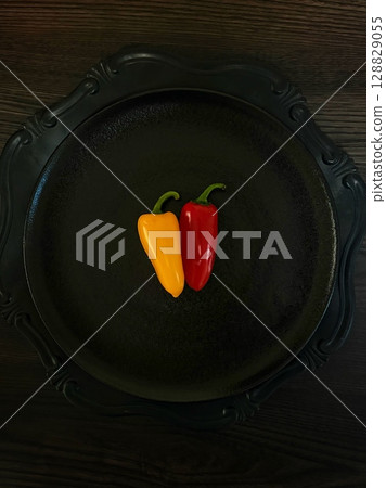 Beautiful yellow and red colorful peppers placed on a black plate 128829055