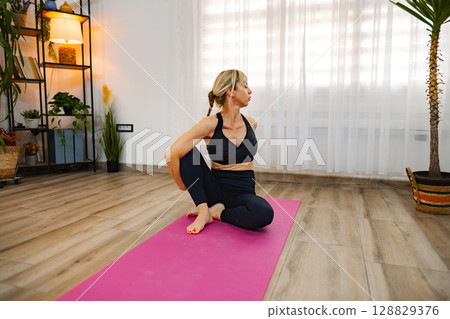 Engaging in a calming yoga pose in a serene indoor space 128829376