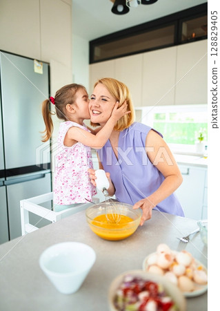 Joyful cooking moments shared between mother and daughter 128829405