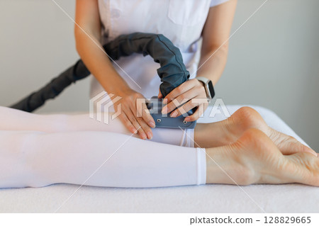 Woman in special white suit getting anti cellulite massage in a spa salon. LPG, and body contouring treatment in clinic.Reset body weight with LPG massage. Woman in special white suit getting anti cellulite massage in a spa salon. LPG, and body contouring treatment in clinic.Reset body weight with LPG massage. 128829665