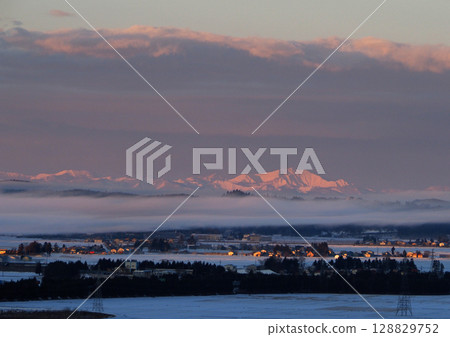 冬日清晨，被朝霞染成粉紅色的雪山和薄霧，景象奇幻而美麗。 128829752