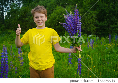 A happy child in yellow is standing amidst a lush field of lupines, radiating 128829915
