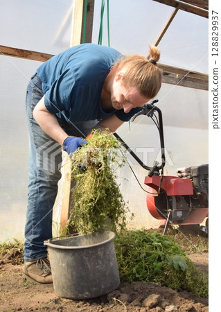 Young man engaged in household chores and small-scale rural farming, tending to his garden with care and dedication. His daily routine reflects a sustainable and self-sufficient way of life 128829937