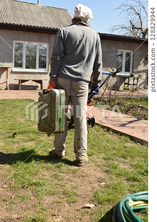 Young man engaged in household chores and small-scale rural farming, tending to his garden with care and dedication. His daily routine reflects a sustainable and self-sufficient way of life Young man engaged in household chores and small-scale rural farming, tending to his garden with care and dedication. His daily routine reflects a sustainable and self-sufficient way of life 128829944