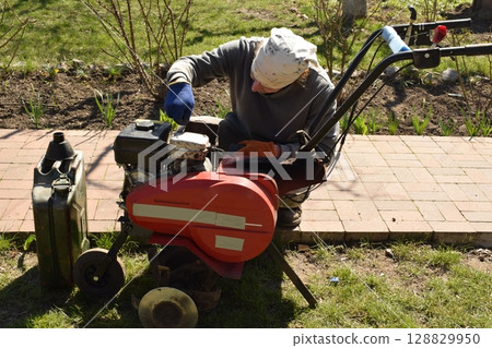 Young man engaged in household chores and small-scale rural farming, tending to his garden with care and dedication. His daily routine reflects a sustainable and self-sufficient way of life Young man engaged in household chores and small-scale rural farming, tending to his garden with care and dedication. His daily routine reflects a sustainable and self-sufficient way of life 128829950