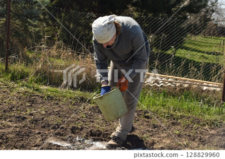 Young man engaged in household chores and small-scale rural farming, tending to his garden with care and dedication. His daily routine reflects a sustainable and self-sufficient way of life Young man engaged in household chores and small-scale rural farming, tending to his garden with care and dedication. His daily routine reflects a sustainable and self-sufficient way of life 128829960
