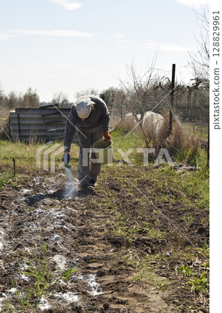 Young man engaged in household chores and small-scale rural farming, tending to his garden with care and dedication. His daily routine reflects a sustainable and self-sufficient way of life Young man engaged in household chores and small-scale rural farming, tending to his garden with care and dedication. His daily routine reflects a sustainable and self-sufficient way of life 128829961