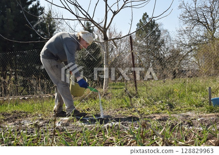 Young man engaged in household chores and small-scale rural farming, tending to his garden with care and dedication. His daily routine reflects a sustainable and self-sufficient way of life Young man engaged in household chores and small-scale rural farming, tending to his garden with care and dedication. His daily routine reflects a sustainable and self-sufficient way of life 128829963