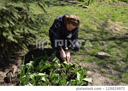 Young man engaged in household chores and small-scale rural farming, tending to his garden with care and dedication. His daily routine reflects a sustainable and self-sufficient way of life Young man engaged in household chores and small-scale rural farming, tending to his garden with care and dedication. His daily routine reflects a sustainable and self-sufficient way of life 128829972