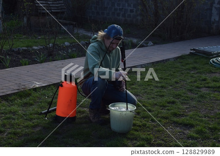 Young man engaged in household chores and small-scale rural farming, tending to his garden with care and dedication. His daily routine reflects a sustainable and self-sufficient way of life 128829989