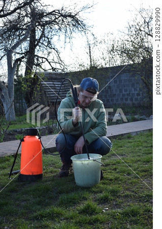 Young man engaged in household chores and small-scale rural farming, tending to his garden with care and dedication. His daily routine reflects a sustainable and self-sufficient way of life 128829990