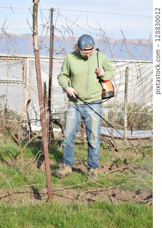 Young man engaged in household chores and small-scale rural farming, tending to his garden with care and dedication. His daily routine reflects a sustainable and self-sufficient way of life 128830012