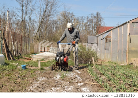 Young man engaged in household chores and small-scale rural farming, tending to his garden with care and dedication. His daily routine reflects a sustainable and self-sufficient way of life Young man engaged in household chores and small-scale rural farming, tending to his garden with care and dedication. His daily routine reflects a sustainable and self-sufficient way of life 128831310