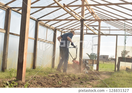 Young man engaged in household chores and small-scale rural farming, tending to his garden with care and dedication. His daily routine reflects a sustainable and self-sufficient way of life Young man engaged in household chores and small-scale rural farming, tending to his garden with care and dedication. His daily routine reflects a sustainable and self-sufficient way of life 128831327