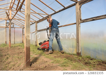 Young man engaged in household chores and small-scale rural farming, tending to his garden with care and dedication. His daily routine reflects a sustainable and self-sufficient way of life 128831335