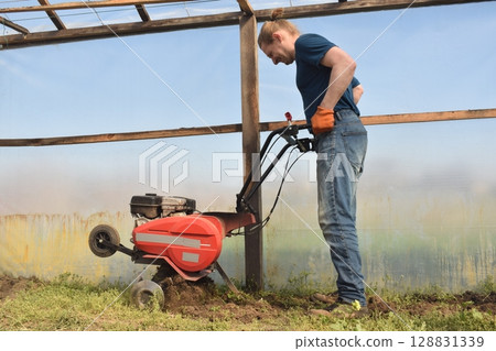Young man engaged in household chores and small-scale rural farming, tending to his garden with care and dedication. His daily routine reflects a sustainable and self-sufficient way of life 128831339
