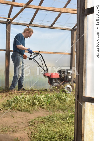 Young man engaged in household chores and small-scale rural farming, tending to his garden with care and dedication. His daily routine reflects a sustainable and self-sufficient way of life 128831345