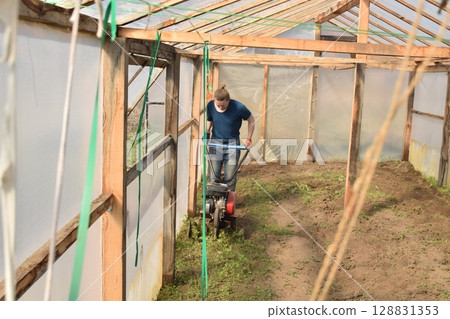 Young man engaged in household chores and small-scale rural farming, tending to his garden with care and dedication. His daily routine reflects a sustainable and self-sufficient way of life 128831353