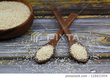 Top view closeup of freshly harvested white sesame in wooden bowl isolated on wooden background with clipping path. 128831954