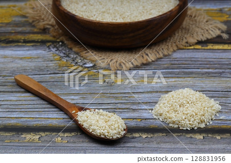 Top view closeup of freshly harvested white sesame in wooden bowl isolated on wooden background with clipping path. 128831956