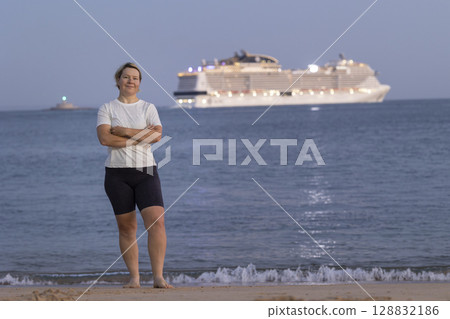 Tourist watching cruise ship leaving from beach at sunset Tourist watching cruise ship leaving from beach at sunset 128832186