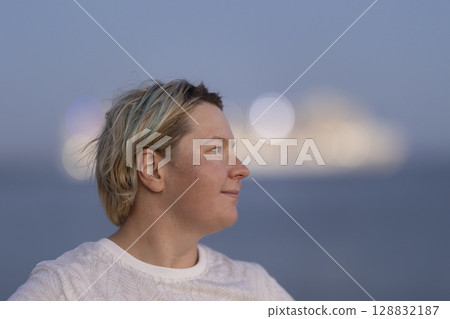 Woman watching cruise ship leaving port at dusk Woman watching cruise ship leaving port at dusk 128832187