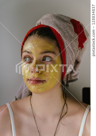 Woman applying turmeric face mask for skin care treatment 128834837