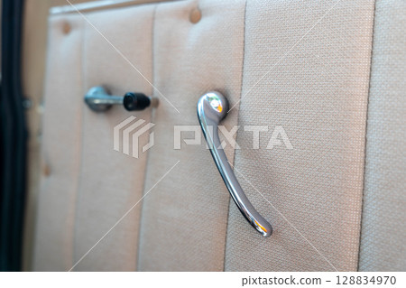 Chrome door handle and window crank in vintage car interior Chrome door handle and window crank in vintage car interior 128834970