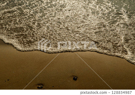 Gentle waves washing golden sand on serene beach Gentle waves washing golden sand on serene beach 128834987