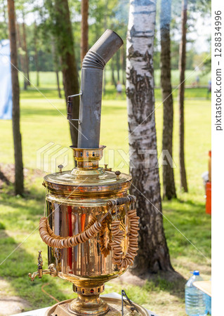 Traditional russian samovar brewing tea outdoors in summer Traditional russian samovar brewing tea outdoors in summer 128834996