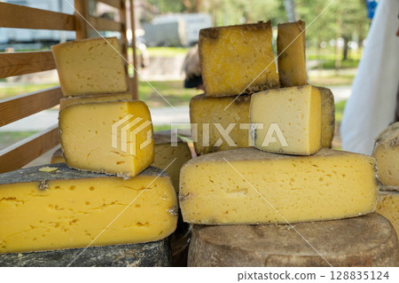 Various cheese wheels and slices displayed at outdoor market 128835124