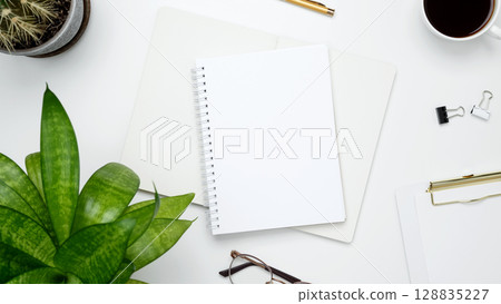 Blank notebook mockup. White workspace with cactus, green plant, eyeglasses, coffee mug for productivity Blank notebook mockup. White workspace with cactus, green plant, eyeglasses, coffee mug for productivity 128835227
