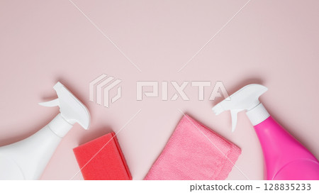 Household cleaning and hygiene concept. Pink cleaning supplies including spray bottles, sponge, and microfiber cloths Household cleaning and hygiene concept. Pink cleaning supplies including spray bottles, sponge, and microfiber cloths 128835233