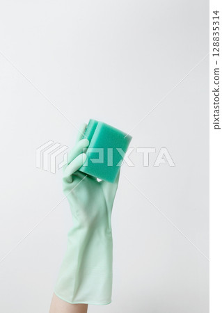 Hand in yellow rubber glove holding a sponge for cleaning. Household cleaning and hygiene concept Hand in yellow rubber glove holding a sponge for cleaning. Household cleaning and hygiene concept 128835314